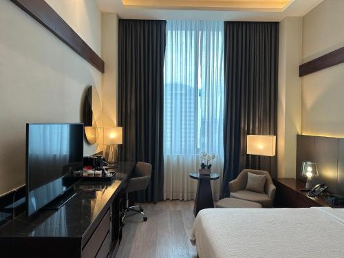 a hotel room with a bed and a desk and a bed and a window at Holiday Inn Santo Domingo by IHG in Santo Domingo