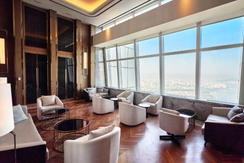 a lobby with chairs and tables and large windows at Signiel Seoul in Seoul
