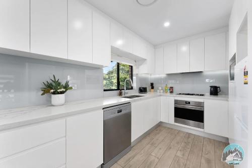 a white kitchen with white cabinets and stainless steel appliances at Aircabin - Guildford - 3 Beds Spacious House in Guildford