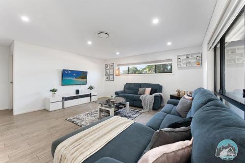 a living room with a blue couch and a table at Aircabin - Guildford - 3 Beds Spacious House in Guildford
