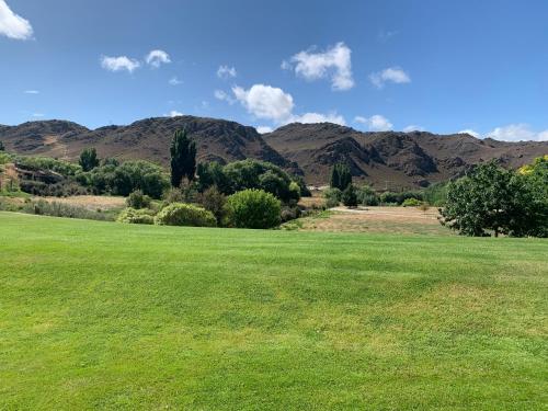 a large green field with mountains in the background at Clock view Apartment in Alexandra