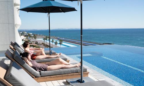 two people laying in lounge chairs next to a swimming pool at Oiso Prince Hotel in Oiso