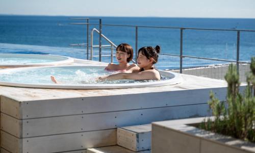 two girls in a hot tub with the ocean in the background at Oiso Prince Hotel in Oiso