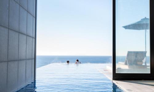two people in a infinity pool with the ocean in the background at Oiso Prince Hotel in Oiso