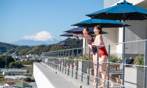 two women standing on a balcony with an umbrella at Oiso Prince Hotel in Oiso