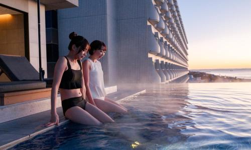 two women sitting in a swimming pool on a building at Oiso Prince Hotel in Oiso
