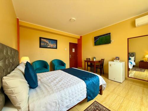 a bedroom with a bed and chairs and a mirror at Hotel Las Palmeras in Huacho