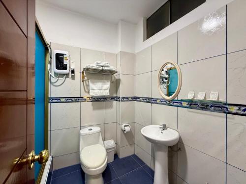 a bathroom with a toilet and a sink at Hotel Las Palmeras in Huacho