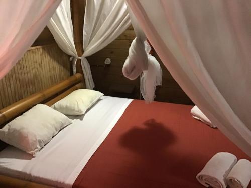 a bedroom with a bed with white curtains and a beduteneway at Lodge Indigo in Le Gosier
