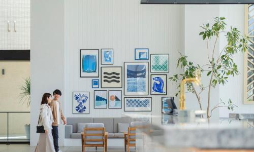 a couple standing in front of a wall with pictures at Oiso Prince Hotel in Oiso