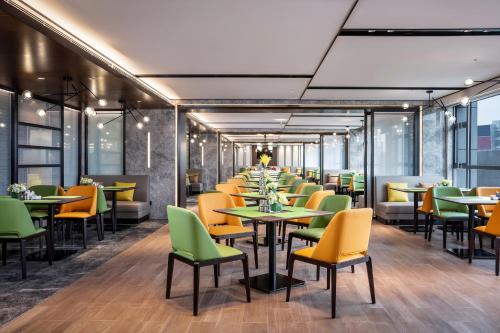 a restaurant with yellow and green chairs and tables at Hampton by Hilton Zhangjiajie Tianmen Mountain in Zhangjiajie