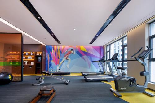 a gym with cardio equipment and a colorful wall at Hampton by Hilton Zhangjiajie Tianmen Mountain in Zhangjiajie