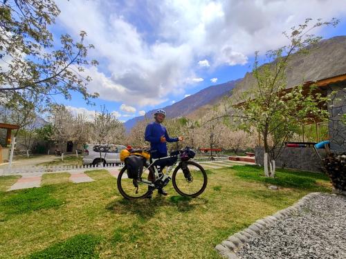 a man standing next to a bike in the grass at Das-e-Basi in Gilgit