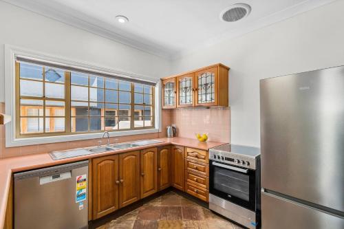 a kitchen with wooden cabinets and a stainless steel refrigerator at Stanwell Park Escape - Sprawling Beachfront Living in Stanwell Park
