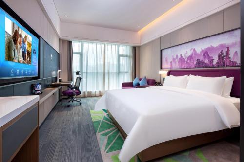 a hotel room with a large bed and a flat screen tv at Hampton by Hilton Zhangjiajie Tianmen Mountain in Zhangjiajie