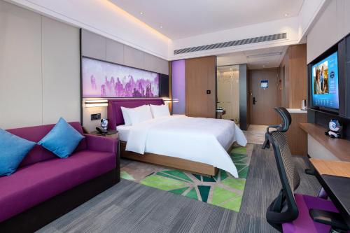a bedroom with a large bed and a purple couch at Hampton by Hilton Zhangjiajie Tianmen Mountain in Zhangjiajie