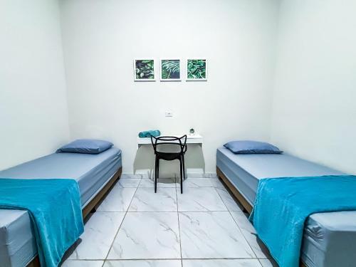 a room with two beds and a table with a chair at Vila Imper Host Itz - Apês com Wi-fi I A/C a 5 min. do Imperial Shopping in Imperatriz