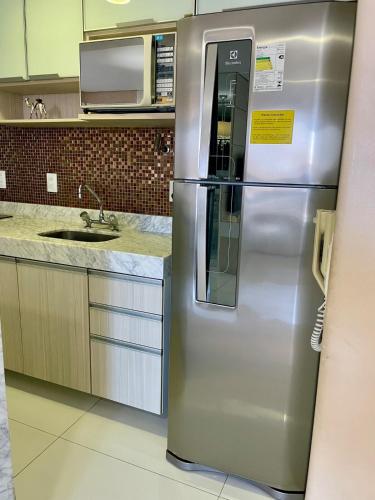 a stainless steel refrigerator in a kitchen with a microwave at Charmosa Cobertura 1103B in Maceió