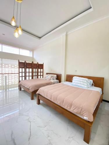 two beds in a room with white walls at Villa Lisha Orolas in Blimbing
