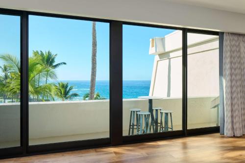 a room with a balcony with a view of the ocean at OUTRIGGER Kona Resort and Spa in Kailua-Kona