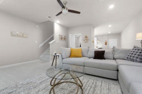 a living room with a couch and a ceiling fan at 3BR 2 & half Bath Townhouse Modern Spacious Retreat Near Lake Conroe! in Conroe