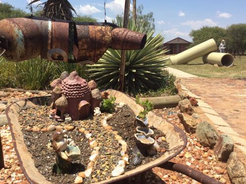 a garden with a rusty fire hydrant and some rocks at Klein Paradys Lodge - Polokwane in Polokwane