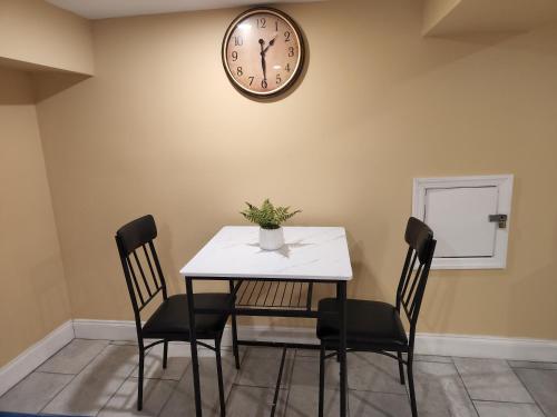 a dining room table with chairs and a clock on the wall at 2kings Apartment in Newark