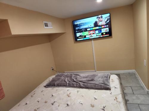 a bedroom with a bed with a flat screen tv on the wall at 2kings Apartment in Newark