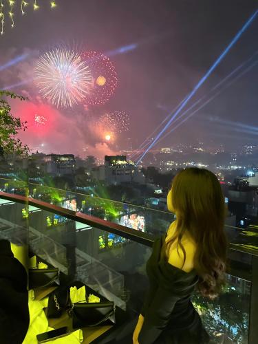 a woman sitting on a ledge looking at fireworks at Hanoi Paon Hotel Spa & Sky Bar in Hanoi