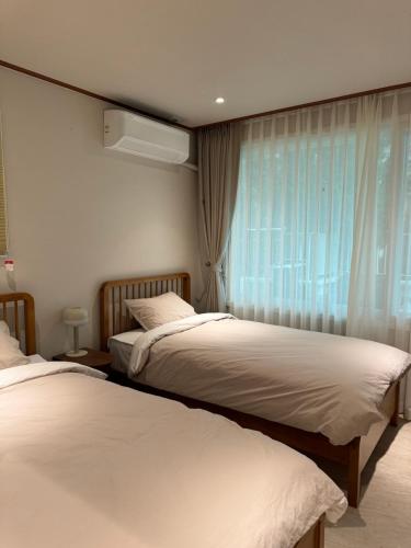 two beds in a hotel room with a window at DADU House in Seoul