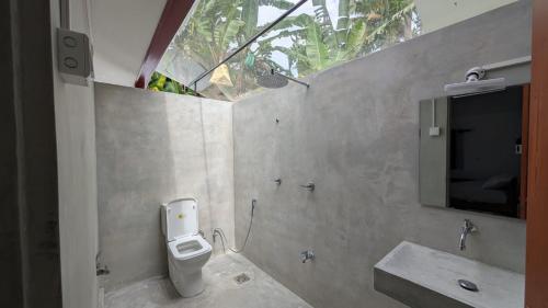a bathroom with a toilet and a sink and a window at Hide Eco Ahangama in Ahangama