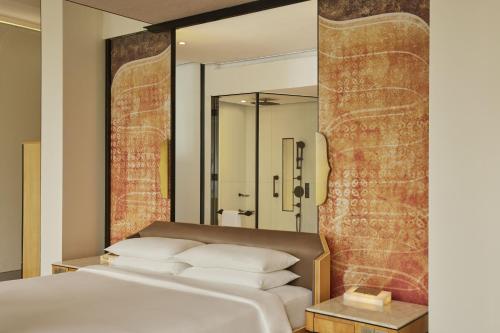 a bedroom with a bed and a large mirror at Keraton At The Plaza, part of The Unbound Collection by Hyatt in Jakarta