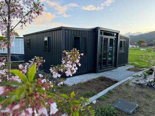 a black container house in a field with flowers at Mount View in Ngaruawahia