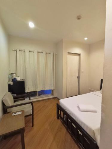 a bedroom with a bed and a chair and a table at Vinary Hotel Sukhumvit in Bangkok