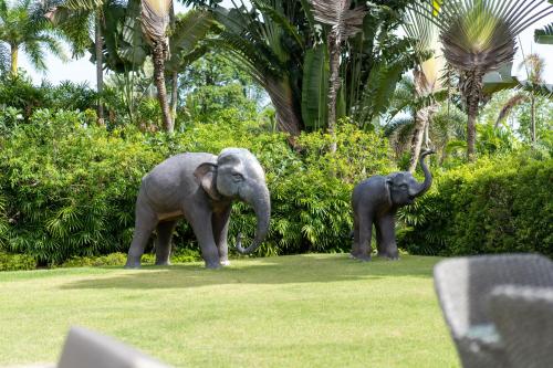 two elephants standing in the grass near some bushes at Luxury 3BR Villa C Layan Estate, Idyllic Retreat near Beach in Layan Beach