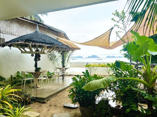 a patio with a table and an umbrella on the beach at Panari Lodge El Nido in El Nido