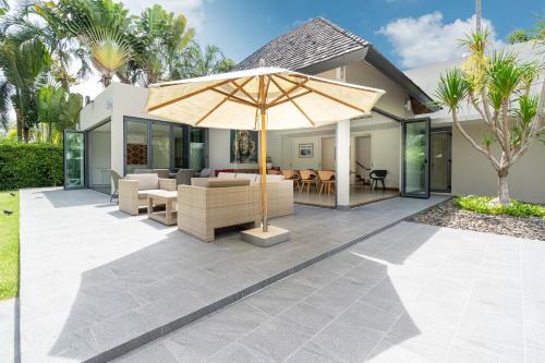 a patio with an umbrella in front of a house at Luxury 3BR Villa C Layan Estate, Idyllic Retreat near Beach in Layan Beach