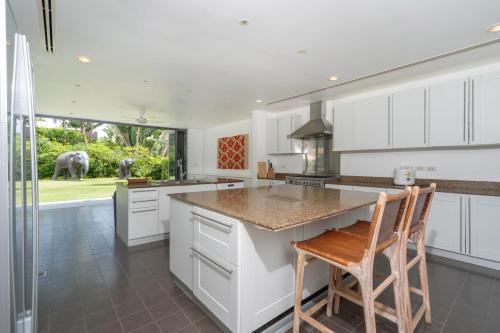 a kitchen with white cabinets and a counter with two chairs at Luxury 3BR Villa C Layan Estate, Idyllic Retreat near Beach in Layan Beach