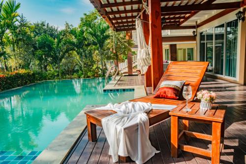 a room with a bed and a table next to a pool at Farinda Resort & Pool Villa in Ban Huai Muang