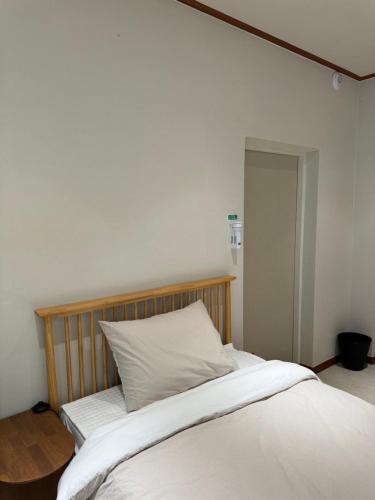a bed with white sheets and a wooden headboard at DADU House in Seoul