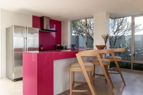 a kitchen with pink cabinets and a table and chairs at Benguela Cove - Oceans Away in Hermanus