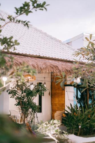 a white house with a straw roof at Sukacita Hill in Uluwatu