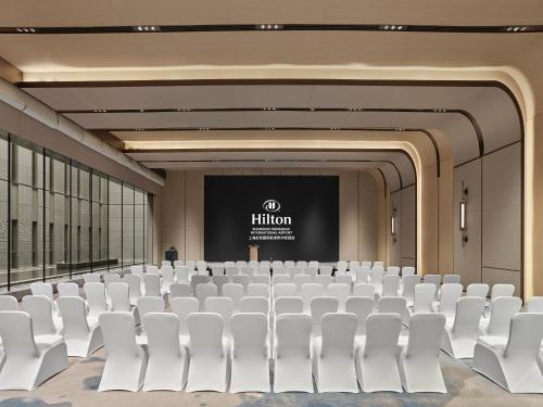 a conference room with white chairs and a screen at Hilton Shanghai Hongqiao International Airport in Shanghai