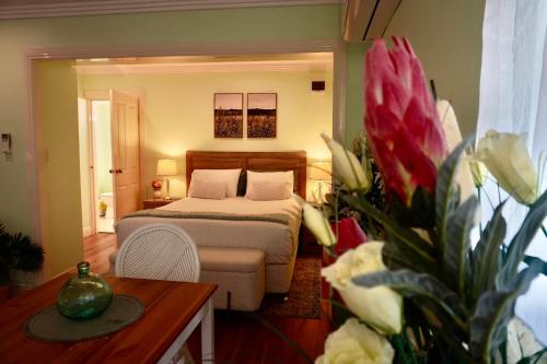 a bedroom with a bed and a table and flowers at Curtis Falls Studio-Apartment in Mount Tamborine