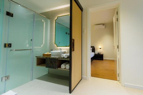 a bathroom with a sink and a glass shower at Le Aqua Resort & Spa Phan Thiet - Swiss Village Resort & Spa in Mui Ne