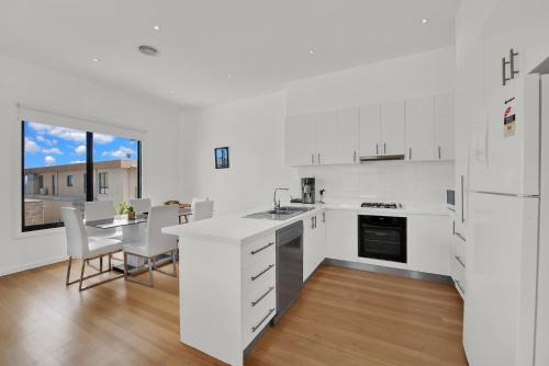 a kitchen with white appliances and a table and chairs at Beach View Escape by Ready Set Stay - BYO LINEN & TOWELS in Safety Beach
