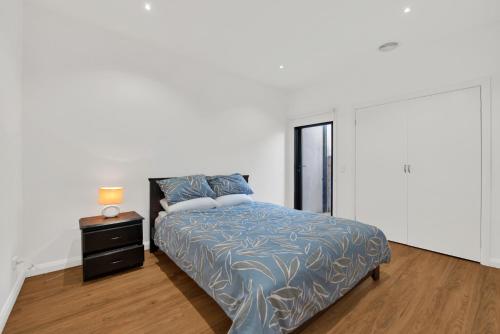 a white bedroom with a bed and a night stand at Beach View Escape by Ready Set Stay - BYO LINEN & TOWELS in Safety Beach