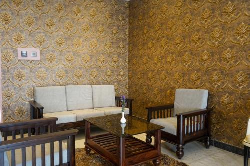 a living room with two chairs and a couch and a table at Hotel Yathin in Mysore