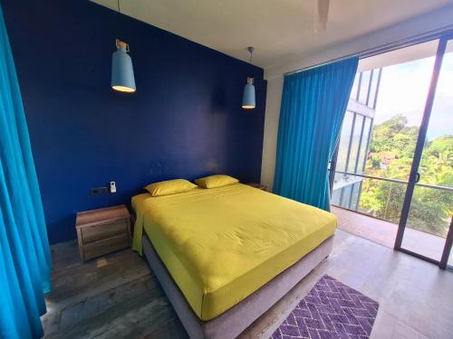a bedroom with a yellow bed and a blue wall at X Mirissa in Mirissa
