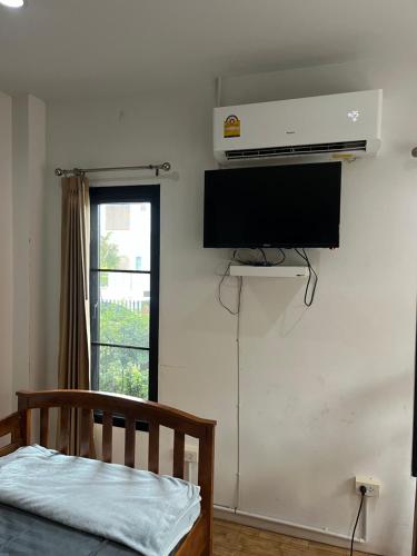a bedroom with a bed and a television on the wall at บ้านสวนรัญจวนสาขาสุราษฎร์ธานี in Ban Huai Chiat